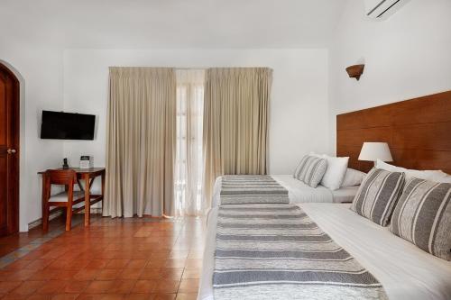 a room with two beds and a table and a television at Hotel Boutique Adela in Granada