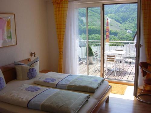 a bedroom with two beds and a balcony with a table at Am Weinberg in Bernkastel-Kues