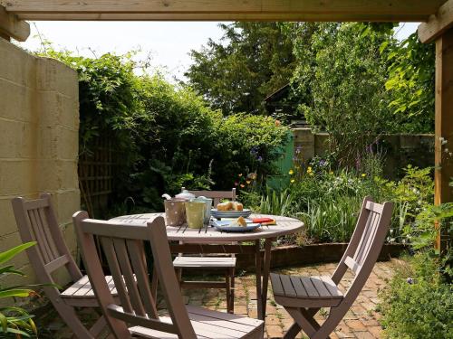 a table and chairs in a garden with a meal on it at Box Cottage in Eastling