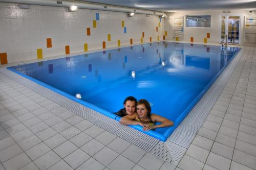 a man and woman laying in a swimming pool at Penzión Limba Donovaly in Donovaly
