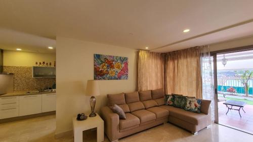 a living room with a couch and a kitchen at Magnolia Luxury Apartment by AltamarHomes in Adeje