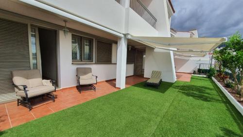 a patio with a lawn with chairs and an umbrella at Magnolia Luxury Apartment by AltamarHomes in Adeje