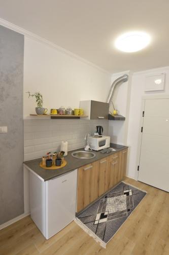 a small kitchen with a sink and a microwave at Apartman Liliom in Subotica