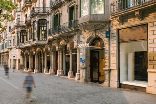 une personne marchant dans une rue devant un bâtiment dans l'établissement Sonder Paseo de Gracia, à Barcelone