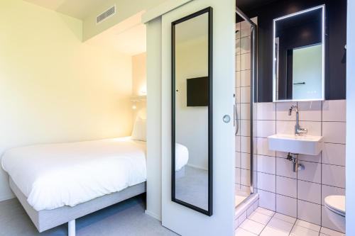 a bathroom with a bed and a sink and a mirror at Graphik Montparnasse in Paris
