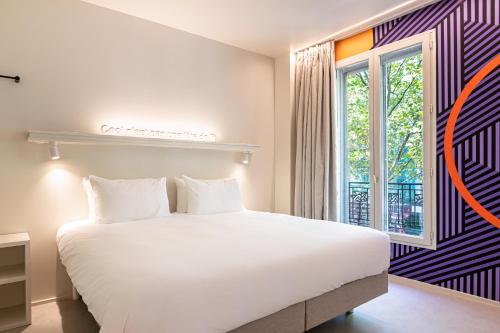 una camera da letto con un grande letto bianco e una finestra di Graphik Montparnasse a Parigi