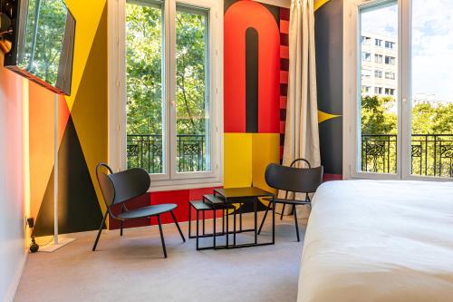 a bedroom with a bed and chairs and windows at Graphik Montparnasse in Paris