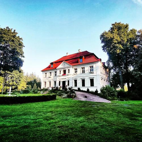 a large white house with a red roof at Pałac Chichy in Małomice