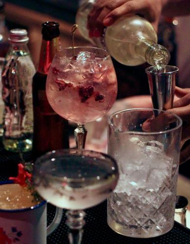 a person pouring a drink into a glass with ice at Hotel Sexto by Icono in Armenia