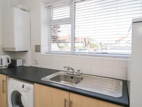 a kitchen with a sink and a washing machine at Seaside Retreat in Prestatyn