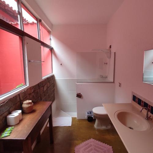 a bathroom with a sink and a toilet and a window at Encantos do Vale Pousada e SPA Cultural in Bueno Brandão