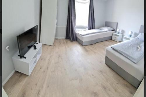 uma sala de estar com uma televisão e um sofá em Schönes neuwertiges 3 Zimmer Apartment - zentral em Wolfsburg