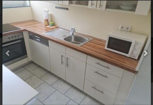 uma pequena cozinha com um lavatório e um micro-ondas em Schönes neuwertiges 3 Zimmer Apartment - zentral em Wolfsburg