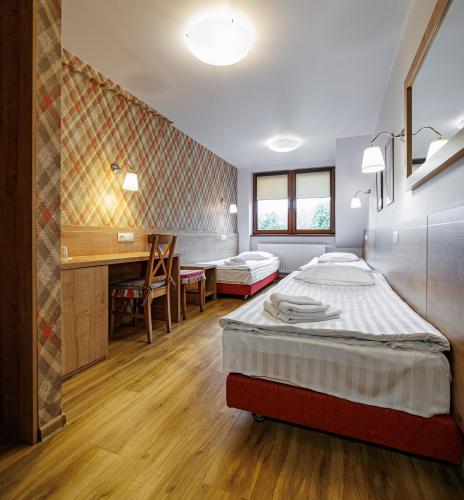a hotel room with two beds and a desk at Leśne Patio in Katowice