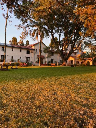 a white building with a tree in the middle of a field at Estancia Turística San Pedro de Timote in Reboledo