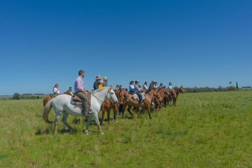 a group of people riding horses in a field at Estancia Turística San Pedro de Timote in Reboledo