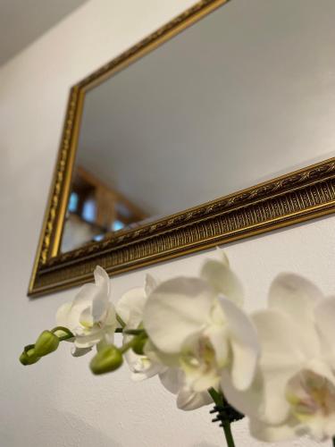 a vase with white flowers in front of a mirror at Flora House Denver in Denver