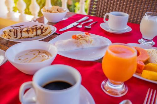 a table with plates of food and cups of coffee and orange juice at Hotel Villa Beija Flor in Jericoacoara