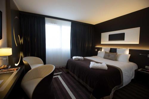 ein Hotelzimmer mit einem Bett und einem Fenster in der Unterkunft Le Colisée Nantes St Herblain in Saint-Herblain