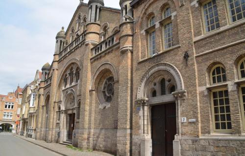 duży ceglany budynek z drzwiami na ulicy w obiekcie The Carmelite w mieście Ypres