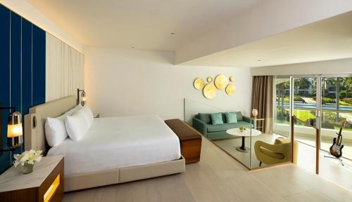 a bedroom with a bed and a living room with a couch at Hard Rock Hotel & Casino Punta Cana - All Inclusive in Punta Cana