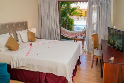a bedroom with a large bed and a television at Hotel Villa Beija Flor in Jericoacoara