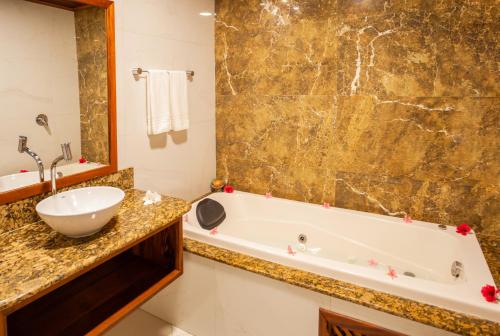 y baño con bañera y lavamanos. en Hotel Villa Beija Flor, en Jericoacoara