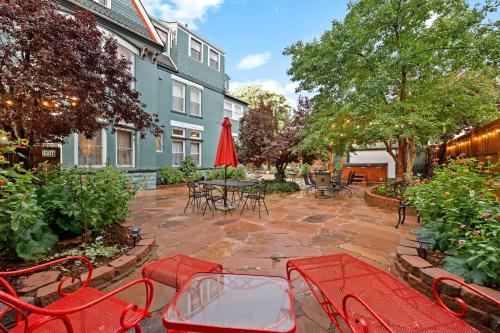a patio with red chairs and tables and a red umbrella at Flora House Denver in Denver
