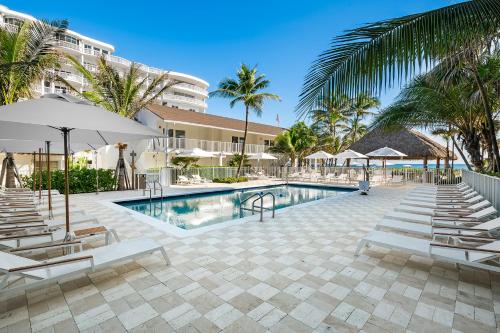 a swimming pool with lounge chairs and a resort at Beachcomber Resort & Club in Pompano Beach