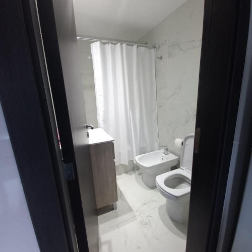 a white bathroom with a toilet and a sink at PELLERANO APARTMENT in Adrogué