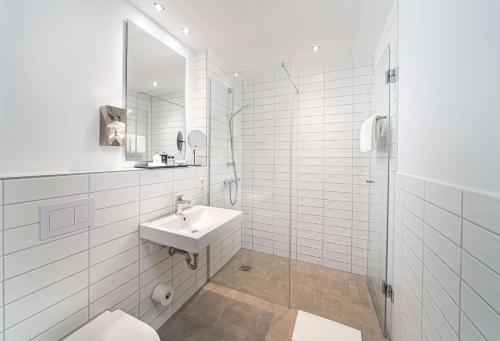 a white bathroom with a sink and a shower at elaya hotel augsburg in Augsburg