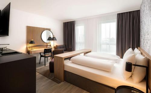 a hotel room with a bed and a desk at elaya hotel augsburg in Augsburg