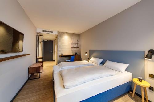 um quarto com uma grande cama branca e uma televisão em elaya hotel goeppingen em Göppingen