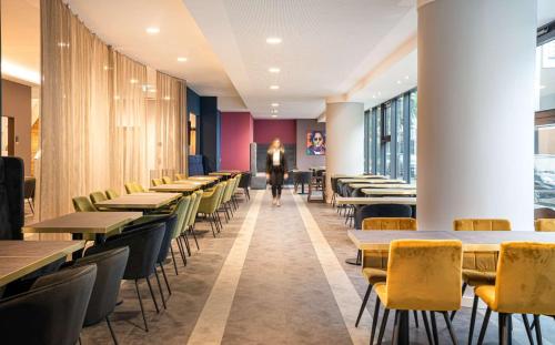 a row of tables and chairs in a restaurant at elaya hotel oberhausen in Oberhausen