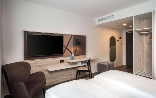 a hotel room with a bed and a tv on a wall at Arthotel ANA Amber in Rostock