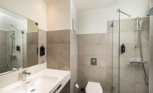 uma casa de banho com um chuveiro, um lavatório e um WC. em Arthotel ANA Amber em Rostock
