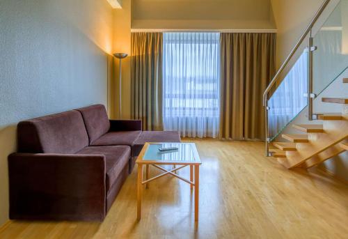 a living room with a couch and a table at elaya hotel frankfurt oberursel in Oberursel