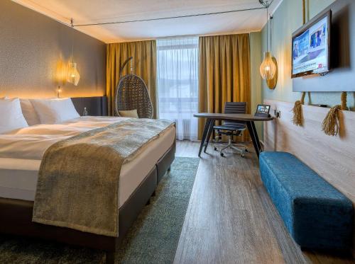 una camera d'albergo con un grande letto e una scrivania di elaya hotel frankfurt oberursel a Oberursel