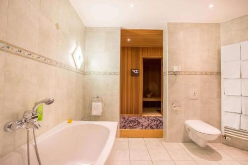 y baño con bañera y aseo. en elaya hotel frankfurt oberursel, en Oberursel