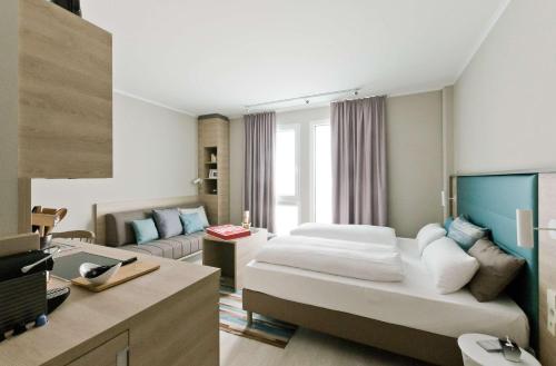 Habitación de hotel con cama y sofá en ANA Living Stuttgart by Arthotel ANA, en Böblingen