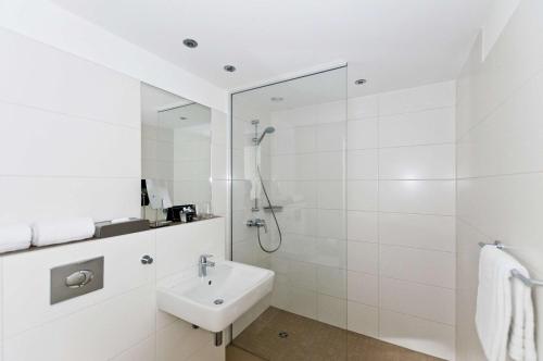 baño blanco con ducha y lavamanos en ANA Living Stuttgart by Arthotel ANA, en Böblingen