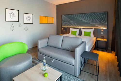 a hotel room with a couch and a bed at elaya hotel kevelaer in Kevelaer