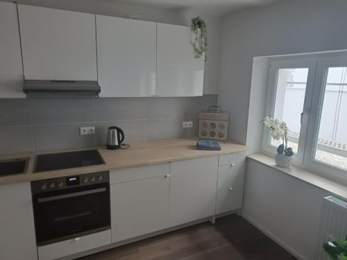 a kitchen with white cabinets and a stove and a window at Apartments & möblierte Zimmer in Kahl am Main, kontaktloser Self Check-in, W-Lan, Schreibtisch, Duschbad, Küchenzeile, PKW-Plätze in Kahl am Main