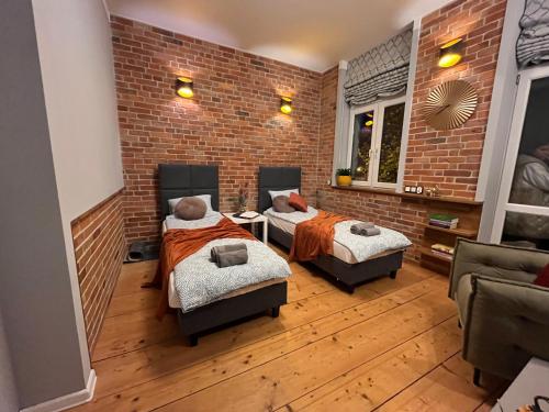 two beds in a room with a brick wall at Apartament przy Ratuszu in Barczewo