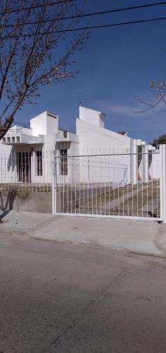 a white fence in front of a white house at Sierras Altas Alojamientos in Villa Carlos Paz