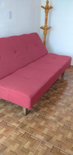 Sofá rosa en una habitación con suelo de madera en Sierras Altas Alojamientos en Villa Carlos Paz