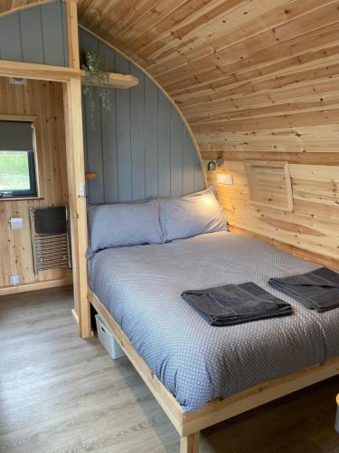 a bed in a cabin with a wooden ceiling at Mowbray Cottages & Glamping in South Kilvington