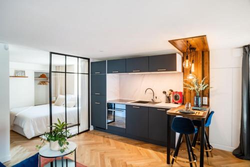 a kitchen with black cabinets and a bed in a room at Charmant Studio paisible dans le Centre du Village in Échenevex