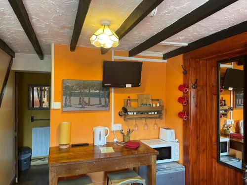 uma cozinha com paredes cor de laranja e uma mesa de madeira em Yarm cottages byre/paddock em Kirk Leavington
