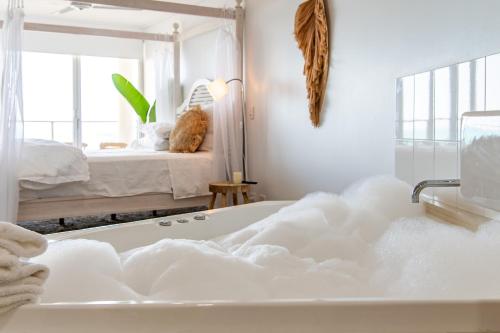 The Top Floor Luxury accomodation for 2 Spa Bath في شاطئ إيرلي: حمام ابيض مع حوض استحمام وسرير